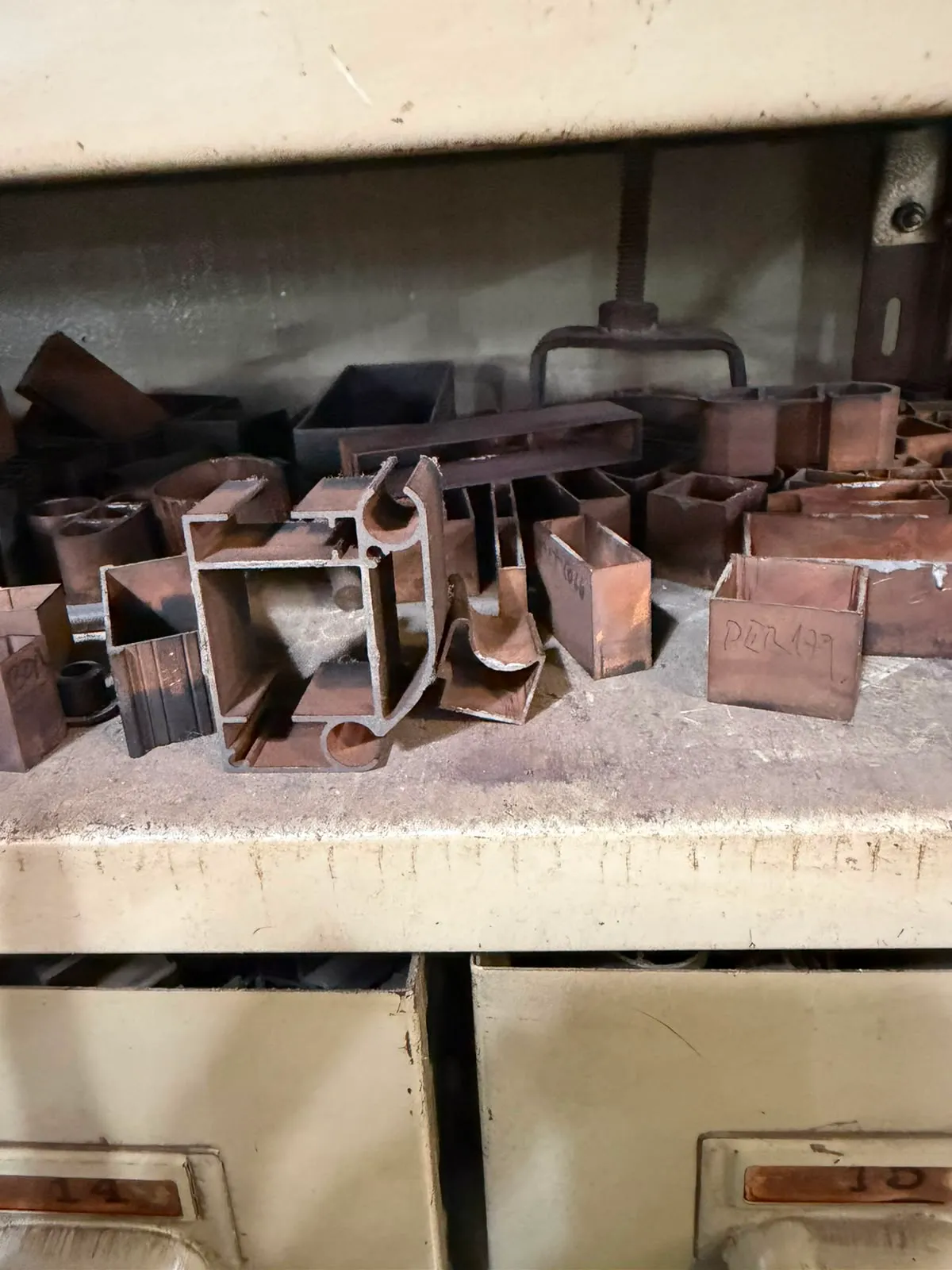 Estante con matrices de extrusión de acero, una con la sección del perfil calada